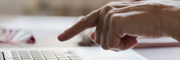 Eine Laptoptastatur. Über der Laptoptastatur sieht man einen Finger, da der User im Begriff ist etwas zu tippen. 