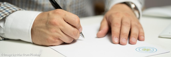 Mann unterzeichnet einen Vertrag. In der Hand hält er einen Stift