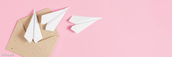 Auf rosafarbenem Hintergrund liegt ein geöffneter Brief. Aus diesem Brief kommen drei weiße Papierflieger. 